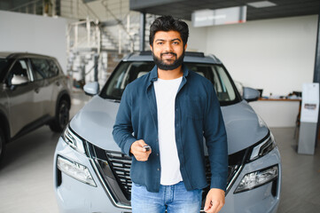 Indian man proudly holding new car key in showroom
