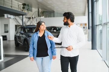 Indian woman discussing car purchase with salesman at dealership