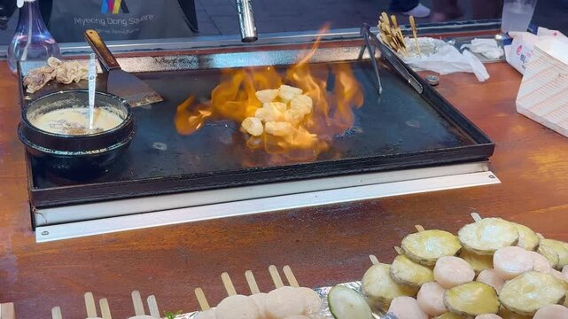 Korean Street Food &ndash; Frying Potato Slices with Red Chili Pepper on Hot Griddle at Outdoor Market