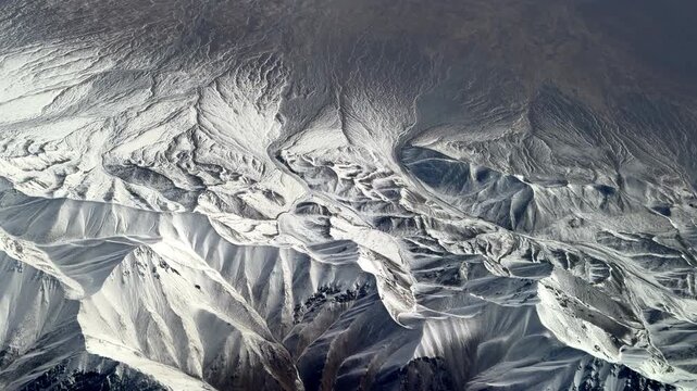 Stunning window seat view of massive snow-covered mountain ranges in Northwest China during a flight. 