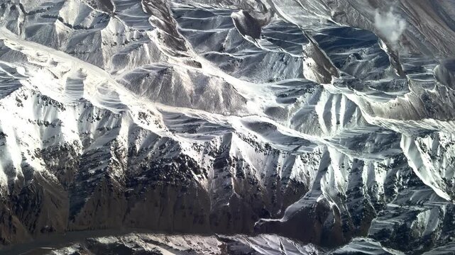 Stunning window seat view of massive snow-covered mountain ranges in Northwest China during a flight. 