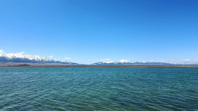 Beautiful scenic view of Sayram Lake with turquoise water and snow-capped Tianshan mountains in Xinjiang, China.