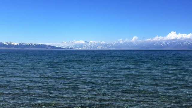 Beautiful scenic view of Sayram Lake with turquoise water and snow-capped Tianshan mountains in Xinjiang, China.