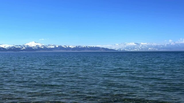 Beautiful scenic view of Sayram Lake with turquoise water and snow-capped Tianshan mountains in Xinjiang, China.