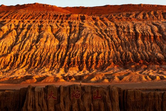 Sunset illuminates layered red rock formations in a desert landscape with Chinese characters carved into the foreground cliff.