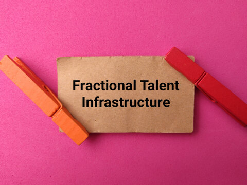 A brown card stating Fractional Talent Infrastructure is held by two wooden pegs against a bright pink background