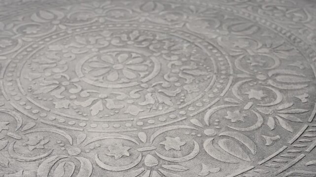 Intricate Embossed Design On Tile Floor. Detailed Floral Medallion Sculpture With Subtle Lighting