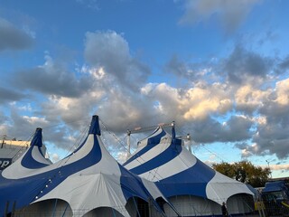 A blue and white circus tent against a cloudy sky. The inscription "Circus" in Russian © Olga