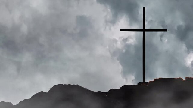 Silhouette of Christian Cross on Rocky Mountain Peak Against Dark Storm Clouds Background