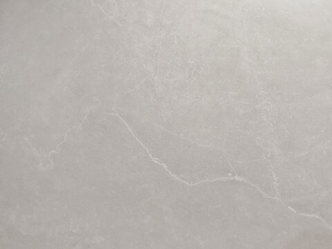 A high-resolution, sharp photograph of a sophisticated natural grey marble or travertine stone surface. It features elegant, fine white crystalline veining that creates a dynamic, seamless pattern
