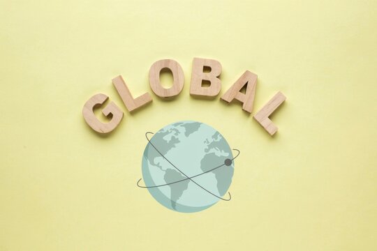 Global word made of wooden letters over stylized earth graphic illustration on yellow background