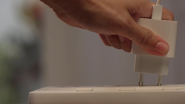 Close up on right side with copy space of woman hand holding adapter, trying to plug into power strip but getting stuck halfway tilted, failure concept.⁠