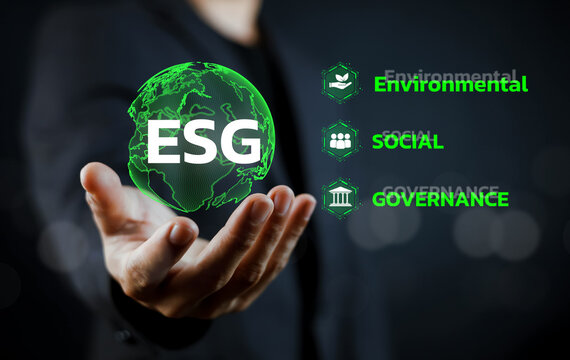 Businessman holding digital ESG (Environmental, Social, Governance) globe hologram and icons. Concept of sustainable corporate development, green economy, and social responsibility investment.
