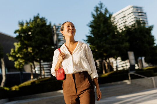 Korean woman enjoying a sunny day while walking in an urban park setting