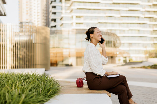 Korean woman enjoying a sunny day while talking on her phone outdoors
