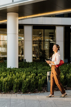 Korean woman walking through a modern urban landscape with bright smile