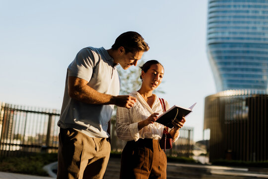 Couple enjoying a sunny day, sharing a moment over a book in the city