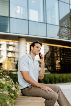 Man enjoying a sunny day while chatting on his phone in a modern city