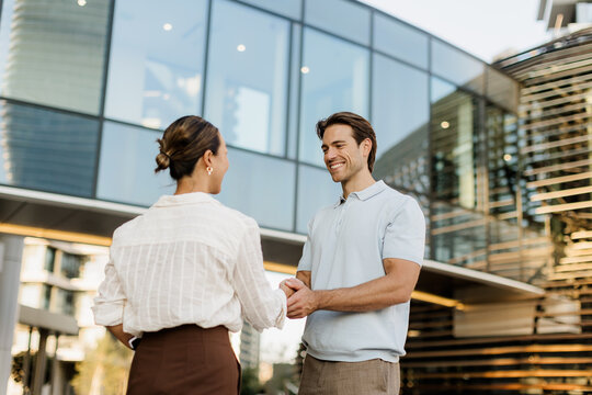 Joyful handshake between friends in a modern urban setting at sunset