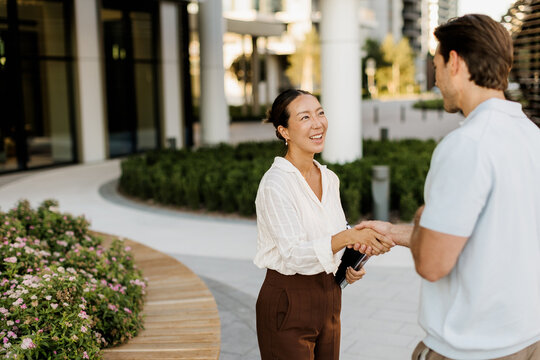 Warm greetings between two friends in a sunny modern urban setting