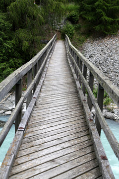 Wooden bridge crossing turquoise stream in lush forest scenery