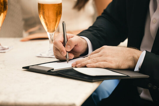 Businessman signs a bill in a leather folder at a restaurant table