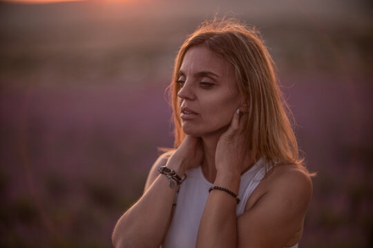 Contemplative woman golden hour portrait standing in beautiful lavender field at dusk