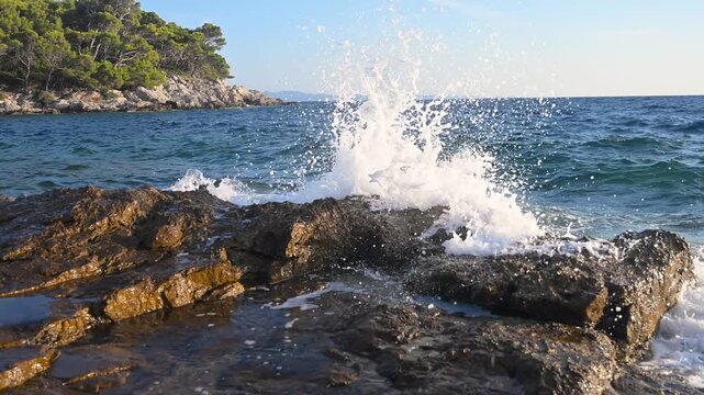 Powerful sea waves crashing against rocky coast of an island. Scenic view of ocean waves hitting rocks on a wild shore. Dramatic sea waves splashing on rocky cliffs