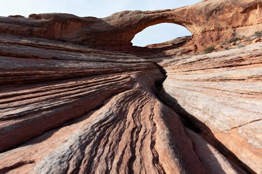 Natural sandstone arch formation with layered rock textures and erosion patterns in a desert landscape