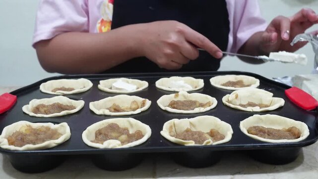Female Hands Filling Individual Cakes with Cream Cheese and Apple Jam