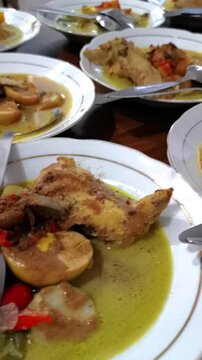 Vertical pan over dozens of plated traditional Indonesian chicken curry dishes ready for catering service in commercial kitchen