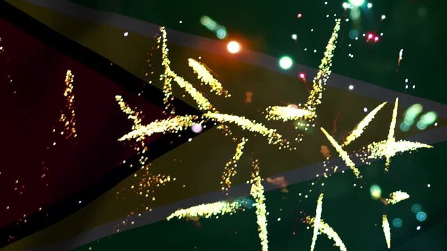 Bright golden fireworks exploding in the night sky over the national flag of Guyana