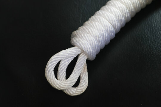 White rope loop with tightly wrapped cord end on black textured surface, showing detailed fiber texture and practical handmade construction for outdoor or utility use