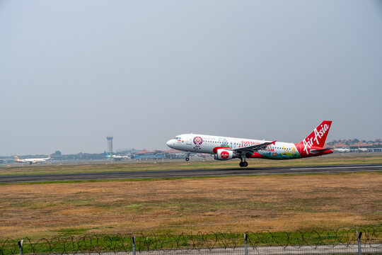 Jakarta, Indonesia - August 22, 2026: An AirAsia Airbus A320 in ASEAN livery lands under a hazy sky during the dry season at Soekarno-Hatta International Airport.