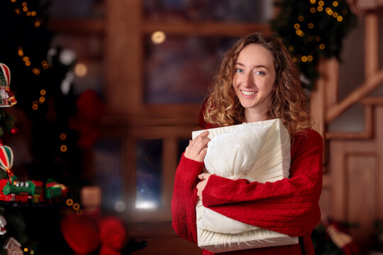 Happy Smiling young woman with curly hair holding a Christmas gift in a cozy festive home setting