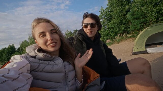 Portrait of young adult Caucasian friends smiling and talking to camera while camping on sandy beach. Clip is ideal for outdoor recreation, travel gear, and youth lifestyle marketing campaigns
