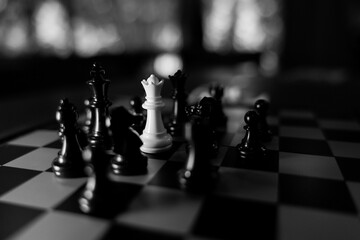 Dramatic chess game with white queen among black pieces on checkered board, creating strategic monochrome scene with strong contrast and cinematic lighting © CoreRock