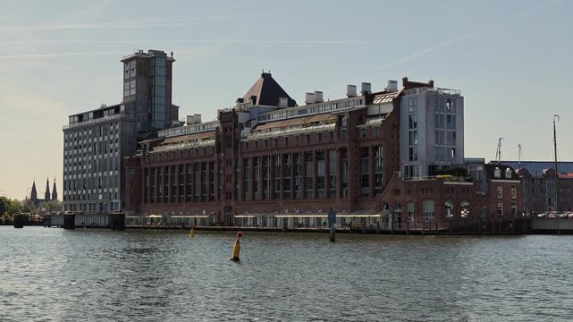 Netherlands - 23 august 2026, Amsterdam: Historical Factory Exterior Along IJ Waterfront Dolly Left