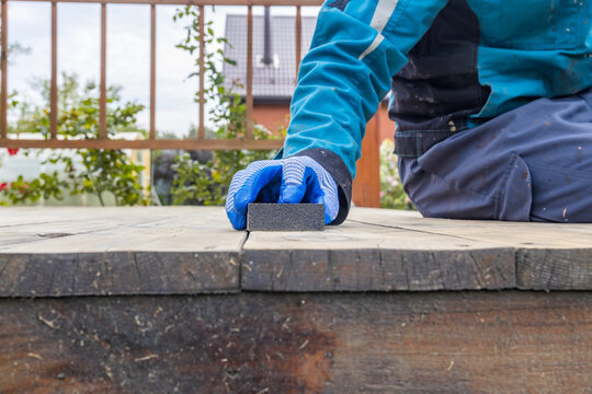Close-up of person cleaning wooden deck with stone abrasive block