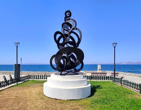 Photo of &ldquo;Polykyklo,&rdquo; an abstract iron sculpture created in 2005 by Greek artist Nikos-Giorgos Papoutsidis, featuring intertwined metal circles along the Flisvos coastal promenade.