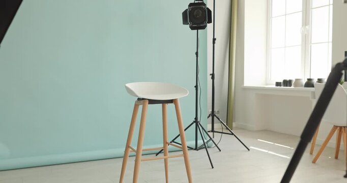 Studio backdrop lighting tripod softbox stool equipment. Clean photography setup in bright interior with seamless mint paper and tripods for portraits. Clear commercial studio setup concept.