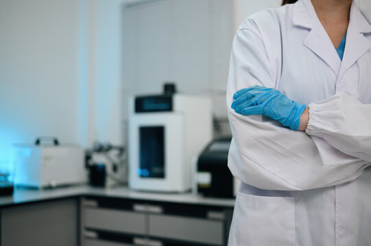 Cropped of confident Scientist in White Lab Coat and Blue Gloves Standing Arms Crossed in Modern Laboratory