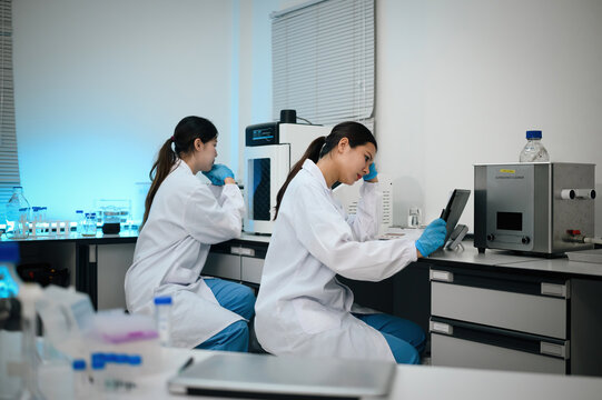Stressed Two Female Asian Scientists Working in Modern Research Laboratory with Advanced Equipment