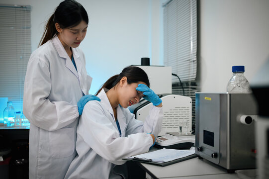 Stressed Female Asian Scientist Comforted by Colleague in Modern Research Laboratory