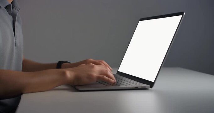 Man typing on gray laptop with blank screen for remote business work now