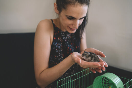 Smiling woman gently holding a small pet hamster in her hands