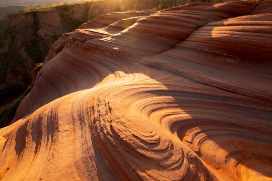 Sunlit sandstone formations with wavy erosion patterns in a desert landscape
