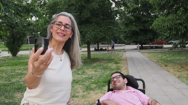 Mother and disabled son video calling together in a park