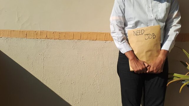 A job seeker in a white shirt gesturing toward a brown envelope with a handwritten need job text. Unemployment, career, and hiring stock video footage.