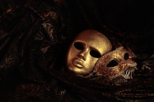 Golden carnival masks on a dark background.